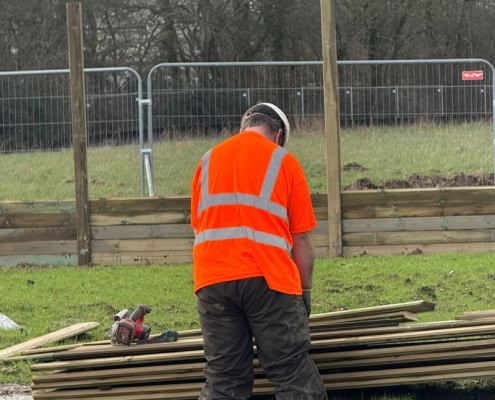 Knight Fencing team member working in waterlogged, muddy ground conditions during a winter timber fencing installation