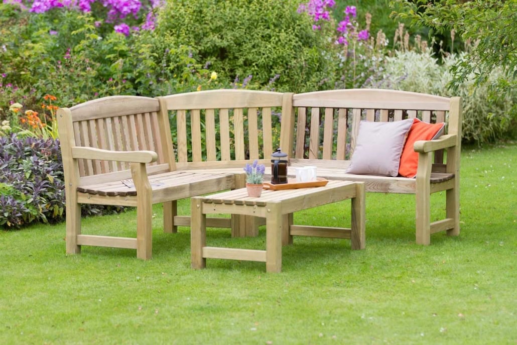Garden Wooden Coffee Table 1 Wooden garden bench with cushions and coffee table in a lush garden setting.