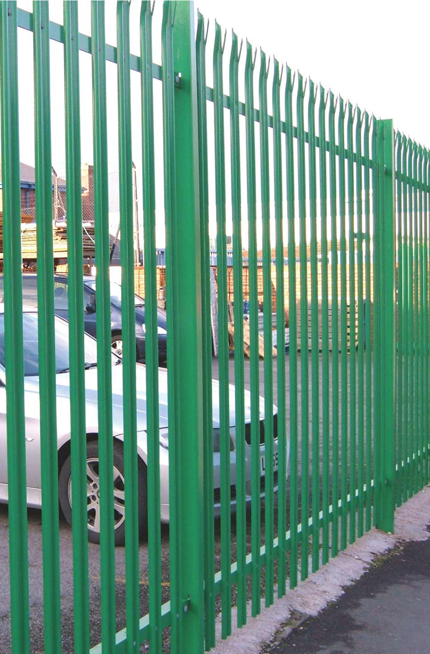 A photo of a green spiked metal fence in an industrial setting