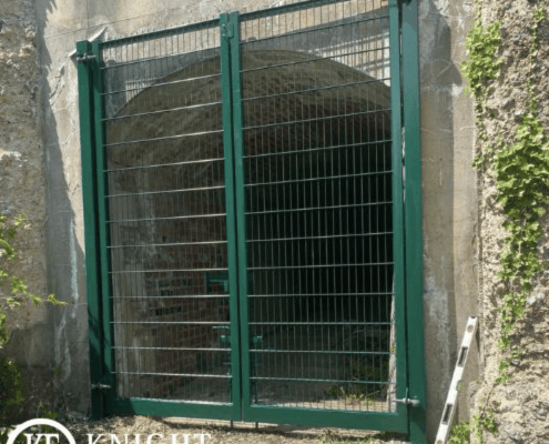 Green mesh security gate installation for an arched tunnel entrance by Knight Fencing.