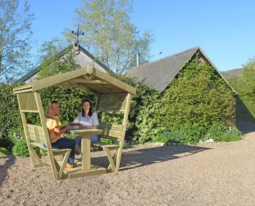Women sitting in Stirling wooden garden gazebo with table and benches