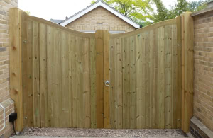bespoke-earnley-timber-driveway-gates-scalloped Made-to-measure Earnley timber driveway gates with a stylish scalloped top, installed between brick walls for a secure property boundary