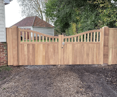 Highleigh hardwood driveway gates installed between matching timber posts, featuring decorative open-top vertical timbers